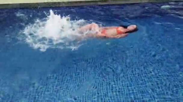 Gyönyörű lány narancssárga fürdőruhában úszik a kék medencében. — Stock videók