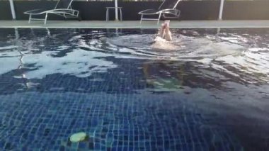 Kız otel havuzunda yüzüyor. Kız havuz kenarında dinleniyor.