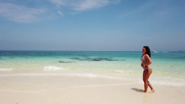 Fille brune marche sur la plage d'une île inhabitée avec de l'eau azur 