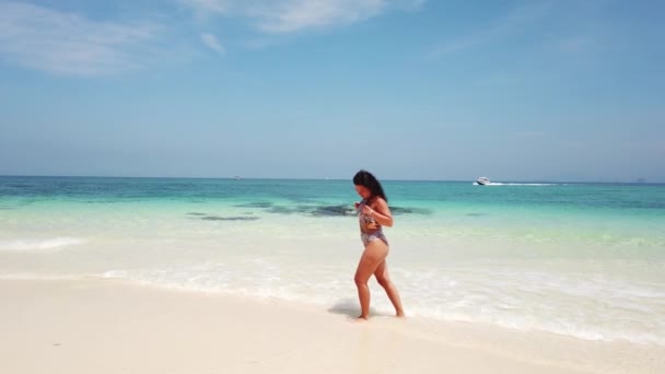 女の子ブルネットは紺碧の水と無人島のビーチを歩く — ストック動画
