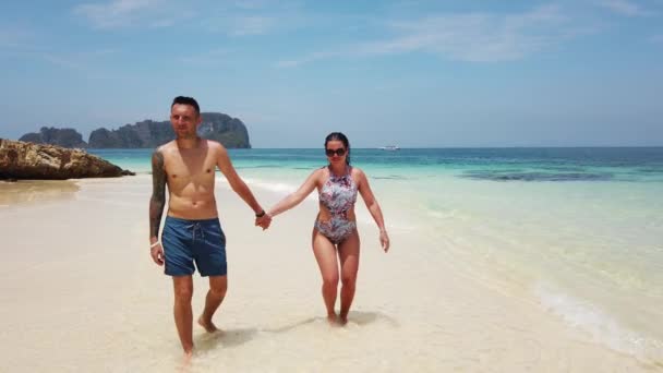 砂漠の島で紺碧の水と一緒にビーチを歩く愛のカップル — ストック動画