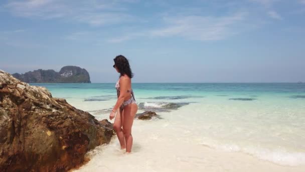 Fille sur la plage d'une île inhabitée à côté d'une grande pierre 
