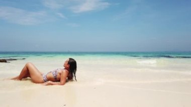 Güzel esmer kız tropik bir adanın sahilinde banyo yapar.