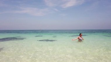 Güzel esmer kız tropik bir adanın sahilinde banyo yapar.