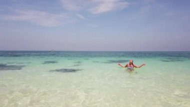 Güzel esmer kız tropik bir adanın sahilinde banyo yapar.