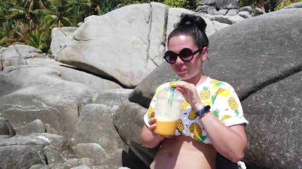 Girl Drinks Fruit Fresh Beach Sitting Large Stone Background Tropics — Stock Video