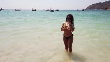 Kız sahilde taze meyve içer.