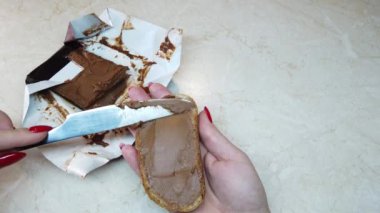 Ağır çekim kız ciabatta dilimine çikolata fındık ezmesi sürüyor.