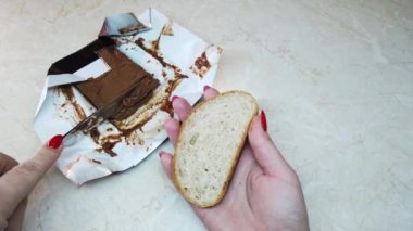 Ağır çekim kız ciabatta dilimine çikolata fındık ezmesi sürüyor.