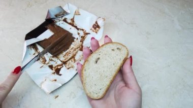 Ağır çekim kız ciabatta dilimine çikolata fındık ezmesi sürüyor.