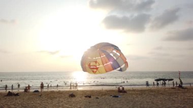 13 Mart 2020, KARON BEACH, PHUKET, THAILAND: Güneşli bir günde kıyıya parasolar kurulmuş, güneşli bir günde güneşlenen ve suda yüzen sayısız turistin bulunduğu tropik plaj.