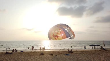 13 Mart 2020, KARON BEACH, PHUKET, THAILAND: Güneşli bir günde kıyıya parasolar kurulmuş, güneşli bir günde güneşlenen ve suda yüzen sayısız turistin bulunduğu tropik plaj.