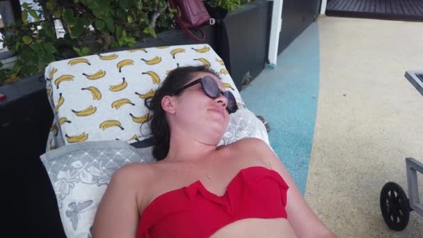 女孩在游泳池边的日光浴床上休息 在游泳池边晒黑 — 图库视频影像