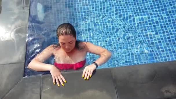 Mladá brunetka plave v bazénu za slunečného dne — Stock video