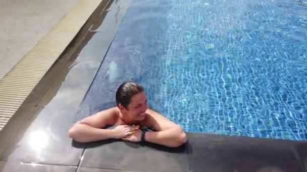 Joven morena nada en la piscina en un día soleado — Vídeos de Stock