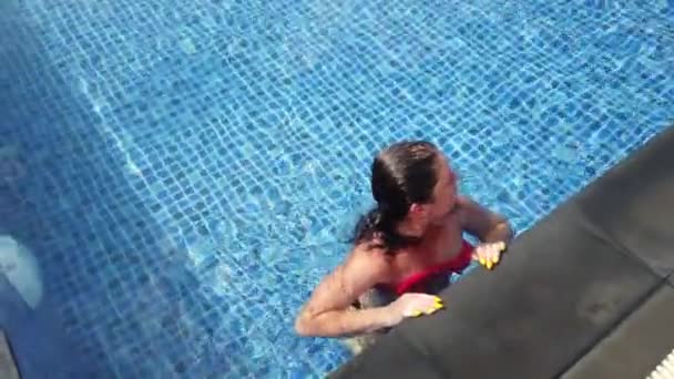 Młoda brunetka pływa w basenie w słoneczny dzień — Wideo stockowe