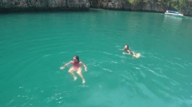 Phi Phi adası yakınlarındaki küçük bir körfezde kızlar açık denizde yüzer.