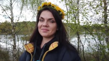 Kafasında karahindiba çelengi olan güzel, gülümseyen esmer kız.