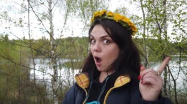 Kafasında karahindiba çelengi olan güzel, gülümseyen esmer kız.