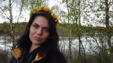 Kafasında karahindiba çelengi olan güzel, gülümseyen esmer kız.