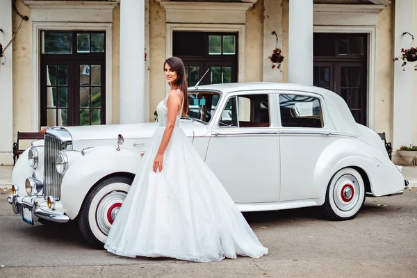 Bride standing by the classic car and smiling — Stock Photo, Image