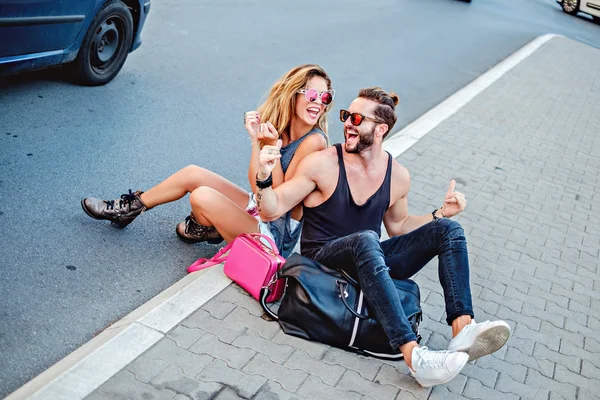 Boldog pár ültünk a járdán, és nevetve — Stock Fotó