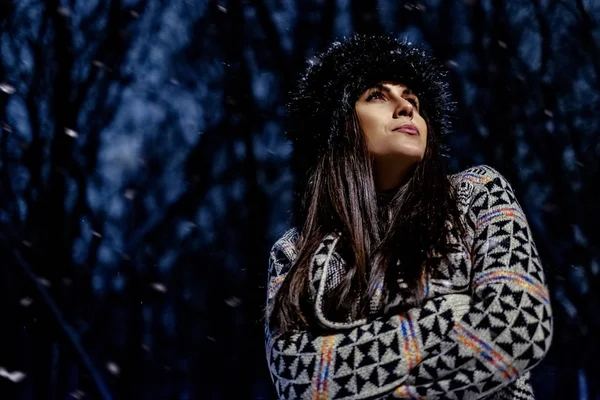 Chica en suéter mirando hacia arriba mientras cae nieve — Foto de Stock