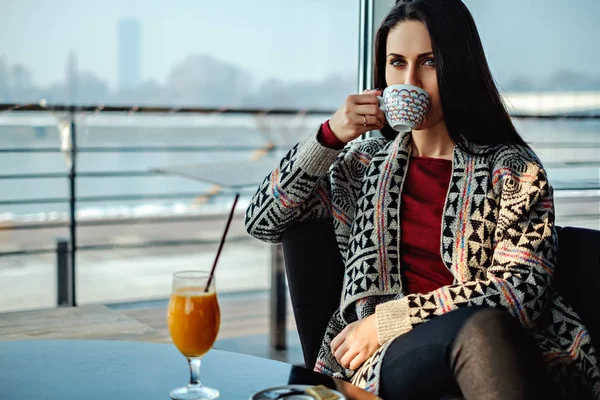 Brunette girl drinking coffee alone in a cafe — Stock Photo, Image