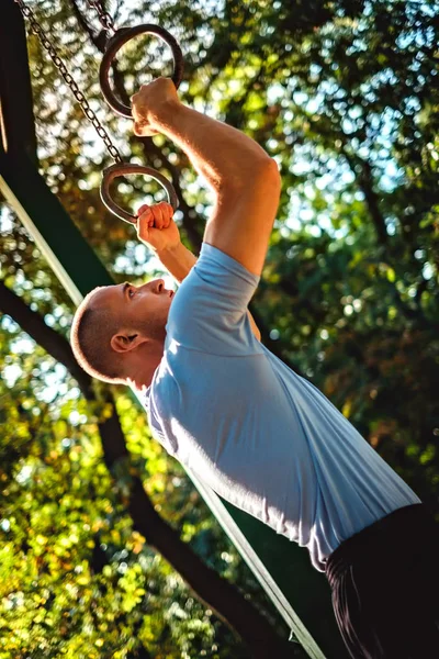 Man training on gymnastics rings in the park