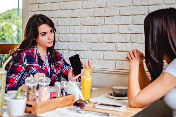 Девушка показывает свой мобильный телефон в ресторане — стоковое фото