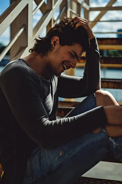 Handsome man smiling while sitting on the stairs — Stock Photo, Image