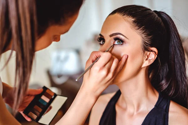 Maquillaje artista aplicando sombra de ojos en una chica — Foto de Stock