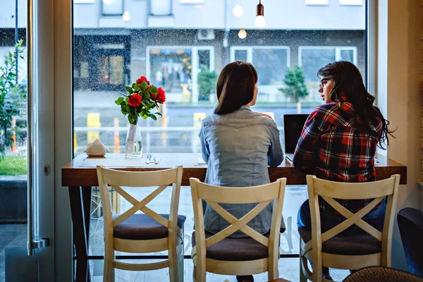 Девушки разговаривают перед ноутбуком в кафе — стоковое фото