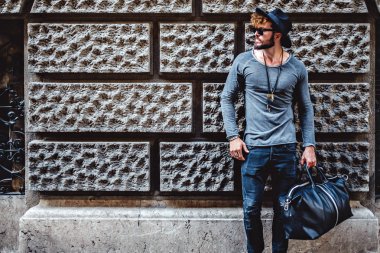 Duvara yaslanmış ve bekleyen hipster adam