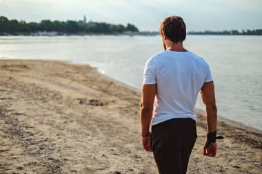 yakışıklı bir adam sahilde yürüyüş