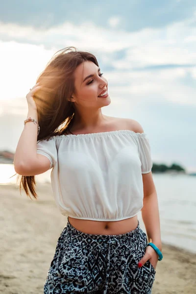 Krásná dívka se dotýká její vlasy se usmívá na pláži — Stock fotografie