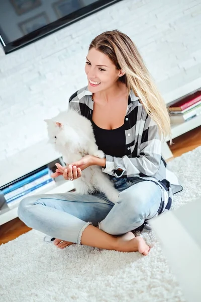 Meisje zittend op het tapijt en spelen met de Perzische kat — Stockfoto