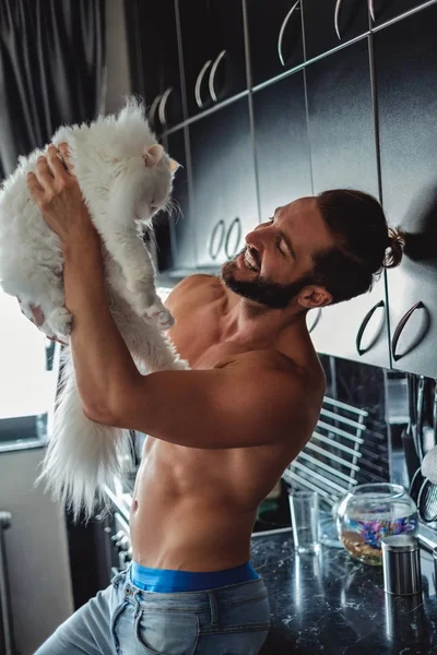 Uomo che tiene il gatto persiano in cucina e sorride — Foto Stock