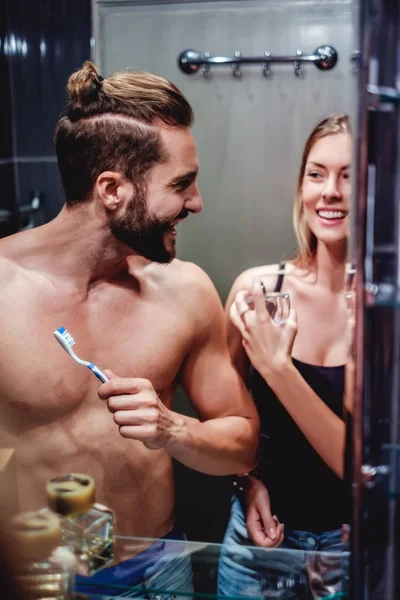 Пара с утренней рутиной и улыбкой в ванной комнате — стоковое фото
