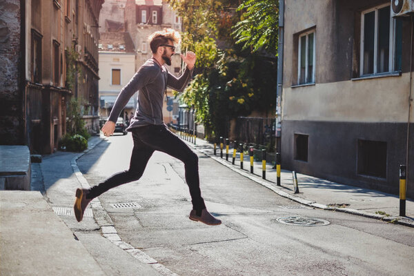 Ecstatic hipster jumps in the street with his mouth open