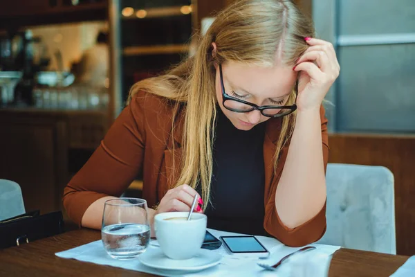 Donna seriamente guardando il telefono cellulare in un ristorante — Foto Stock