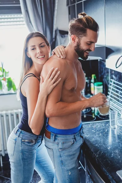 Menina abraçando namorado por trás na cozinha — Fotografia de Stock
