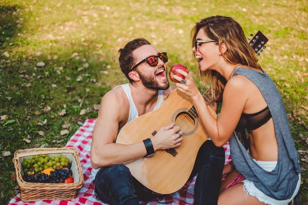 女孩吃苹果给她的男朋友在野餐 — 图库照片