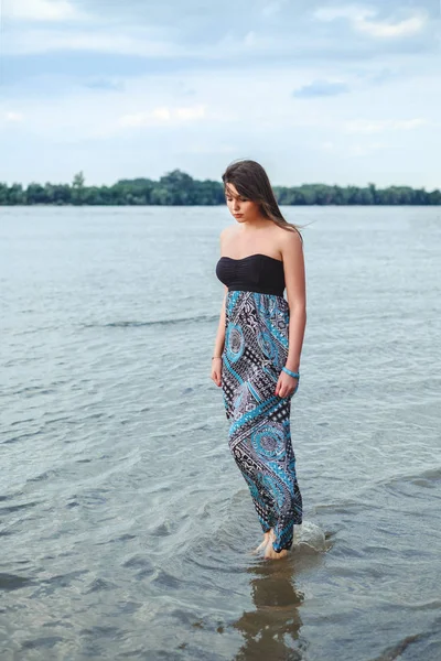 Lány séta egyedül a vízben és a gazdaság ruhája — Stock Fotó
