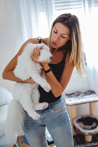 Chica tratando de besar a un gato en su casa — Foto de Stock