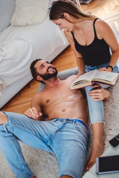 Pareja descansando en el suelo y leyendo un libro — Foto de Stock