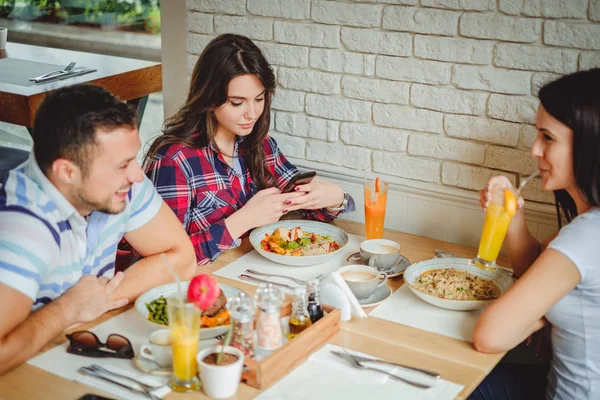 Girl looking at phone while her friends are laughing — Stock Photo, Image
