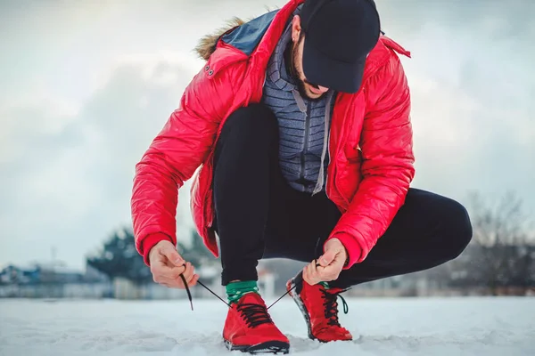 Mann bindet rechten Turnschuh auf schneebedecktem Boden — Stockfoto