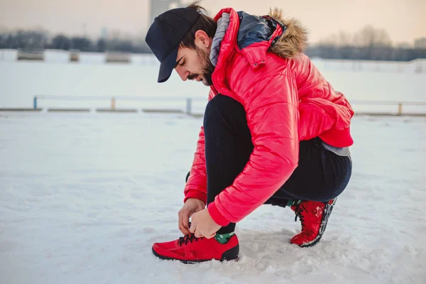 Hombre atando una zapatilla izquierda en un suelo cubierto de nieve —  Fotos de Stock