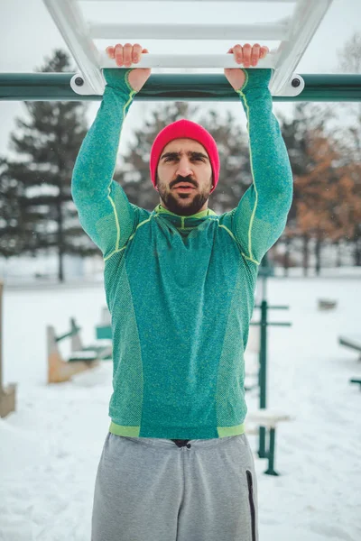 Homem fazendo overhand queixo ups fora em um dia nevado — Fotografia de Stock